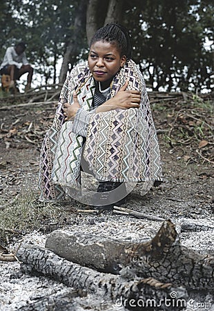 Woman sitting by a the bonfire ashes Stock Photo