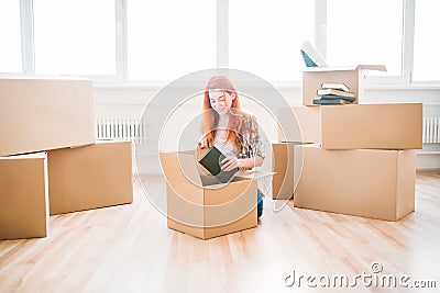 Woman sitting among cardboard boxes, housewarming Stock Photo