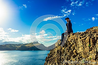 Woman sitting on a cliff on Ponta de Sao Lourenco peninsula, Madeira, Portugal Stock Photo