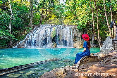 Woman sitting at Erawan waterfall in Thailand. Beautiful waterfall with emerald pool in nature. Stock Photo