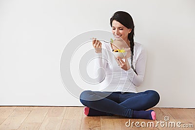 Woman Sitting On Floor Eating Bowl Of Fresh Fruit Stock Photo