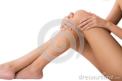 Woman sitting and holding her beautiful healthy long leg with massaging knee and thigh in pain area. Stock Photo