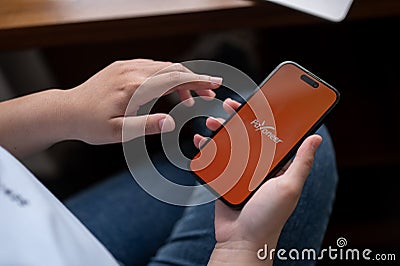 A woman sitting indoors and using a Payoneer application through her Iphone14 Editorial Stock Photo