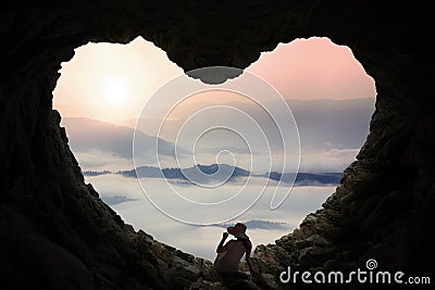 Woman sitting inside cave and enjoy mountain view Stock Photo