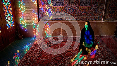 Woman sitting inside with stained glass window reflections of Nasir al-Mulk Mosque, Shiraz, Iran Editorial Stock Photo