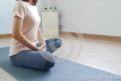 Woman sitting meditation, doing yoga, is alone in the room at home, relax. Practicing meditation Yoga and healthy living concepts Stock Photo