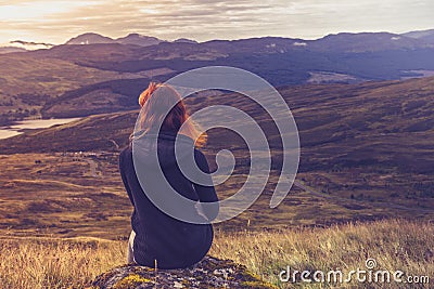 Woman sitting on mountain top and contemplating Stock Photo