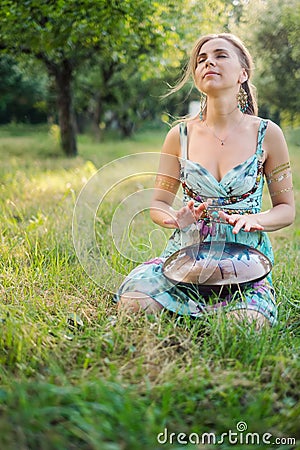 Woman sitting near in the park and playing on happy drum Stock Photo