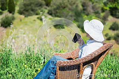 Woman sitting outside on a wicker bench with cup Stock Photo