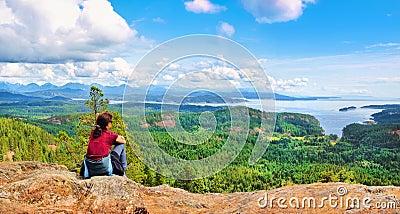Woman sitting on a rock and enjoying the beautiful view on Vancouver Island, British Columbia, Canada Stock Photo