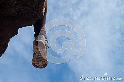 Woman sitting on rock with used running shoes having a break from trailrunning, copy-space on the right Stock Photo