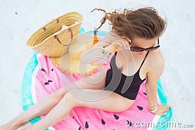 Woman sitting on round watermelon towel and adjusting sunglasses Stock Photo
