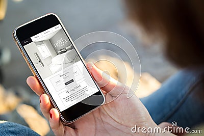 woman sitting in the street browsing hotel website on her smartphone Stock Photo