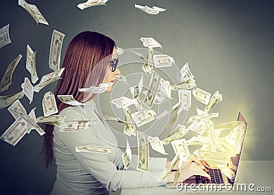 Woman sitting at table using working on a laptop computer making money Stock Photo