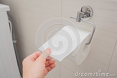 Woman sitting on a toilet in a restroom and rips off a piece of toilet paper from a roll, digestive problems and defecation Stock Photo