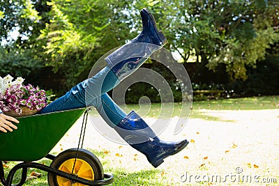 Woman sitting in wheelbarrow at garden Editorial Stock Photo
