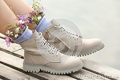 Woman sitting on wooden pier with flowers in socks outdoors, closeup Stock Photo