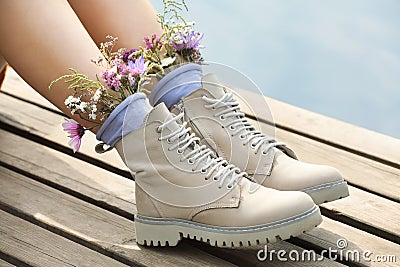 Woman sitting on wooden pier with flowers in socks outdoors, closeup Stock Photo