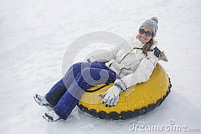 Woman sledding down a hill on a snow tube Stock Photo