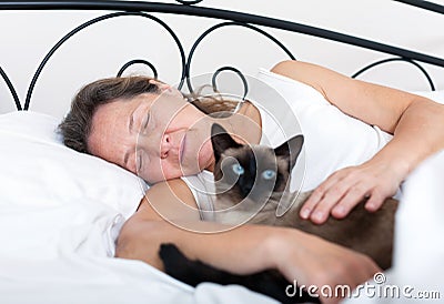 Woman sleeping in embrace with cat Stock Photo