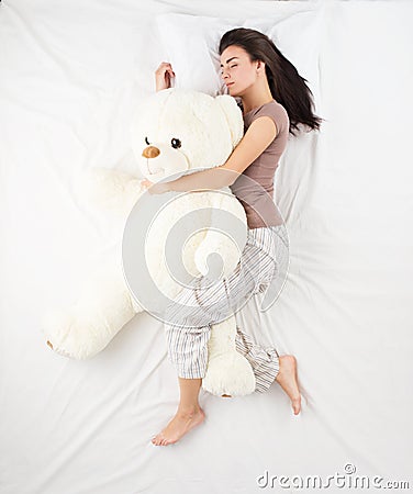 Woman sleeping with large teddy bear Stock Photo