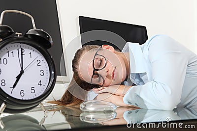 Woman sleeping on work in office desk with clock Stock Photo