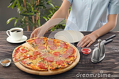 Woman with sliced pepperoni pizza at table Stock Photo