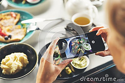 Woman with smart phone taking picture of food at restaurant Stock Photo