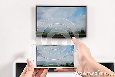 Woman with smartphone connected to TV set Stock Photo