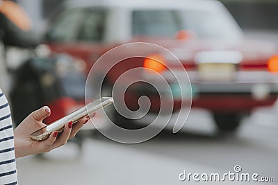 Woman with a smartphone ordering taxi cab or alternative modes of transport. Stock Photo