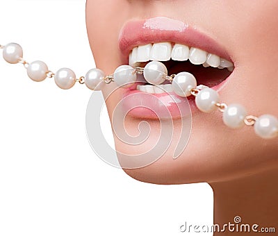 Woman smiles showing white teeth, holding a pearly necklace into the mouth Stock Photo