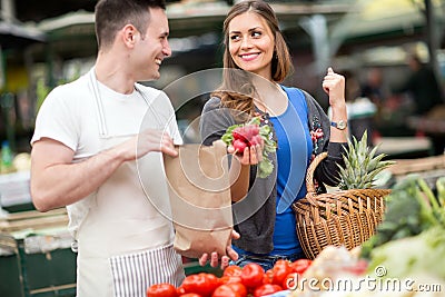 Woman smiling and holding radishes at market Stock Photo