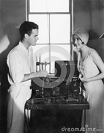 Woman smiling at a man next to an editing machine Stock Photo