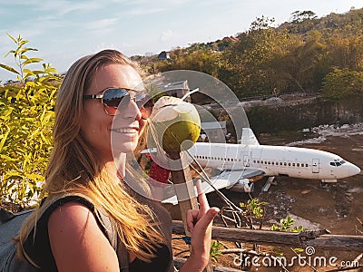 Woman smiling while posing over abandoned airplane in Bali Stock Photo