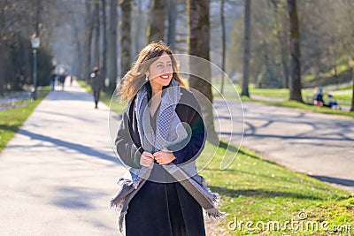 Woman smiling to herself as she strolls through a spring park Stock Photo