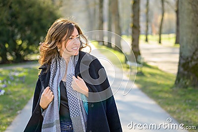 Woman smiling to herself as she strolls through a spring park Stock Photo