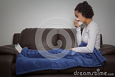 Woman is sneezing. Sitting on the couch. Stock Photo