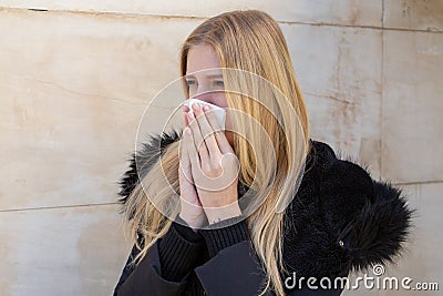 Woman sneezing in winter in black jacket Stock Photo