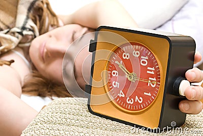 Woman snoozing a red alarm clock Stock Photo