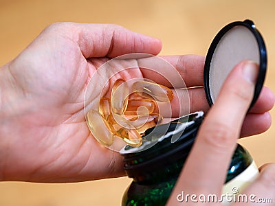 Woman spilling Omega softgel capsules out from a jar to her hand Stock Photo