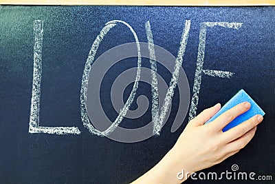 Woman with sponge cleaning from blackboard love concept Stock Photo