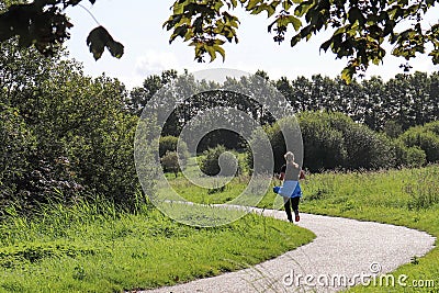 Woman in sportswear is walking along the path in the park on a summer dag. Stock Photo