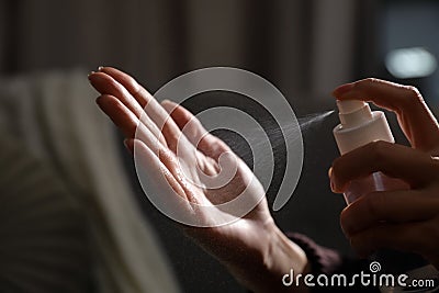 Woman spraying antiseptic onto hand against blurred background, closeup Stock Photo