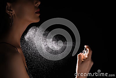 Woman spraying luxury perfume on black background, closeup Stock Photo