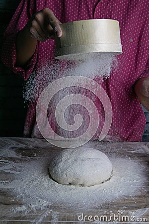 The woman sprinkles the dough from the satiated for the flour, the vocifa bursts and the falling flour. Preparatory process for Stock Photo