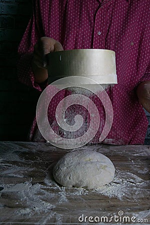 The woman sprinkles the dough from the satiated for the flour, the vocifa bursts and the falling flour. Preparatory process for Stock Photo