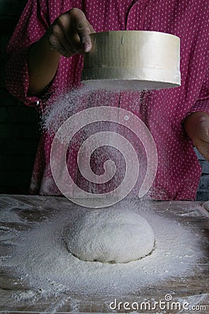 The woman sprinkles the dough from the satiated for the flour, the vocifa bursts and the falling flour. Preparatory process for Stock Photo