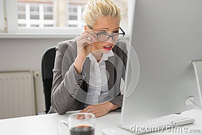 Woman squeezing her eyes to see whats on computer Stock Photo