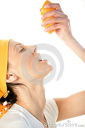 Woman squeezing orange into mouth Stock Photo