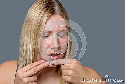 Woman squeezing a pimple on her chin Stock Photo